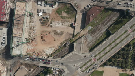 Top-down-footage-of-transport-infrastructure-and-construction-site-in-city.-Cars-driving-on-roads-and-bridge-above-railroad-tracks.-Barcelona,-Spain