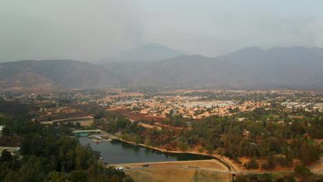 hazy aerial view of a lake and residential area with mountains in the background