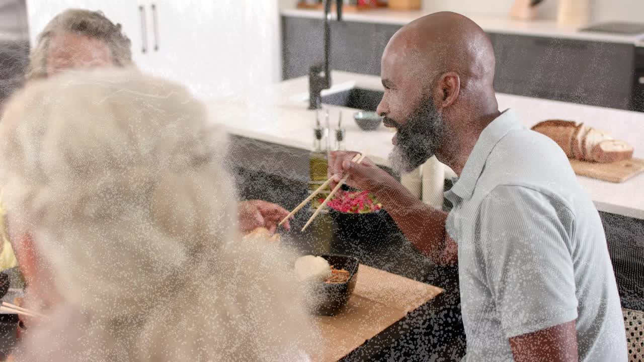 Senior woman in yellow reaching with chopsticks showing tags on platter encouraging food sharing