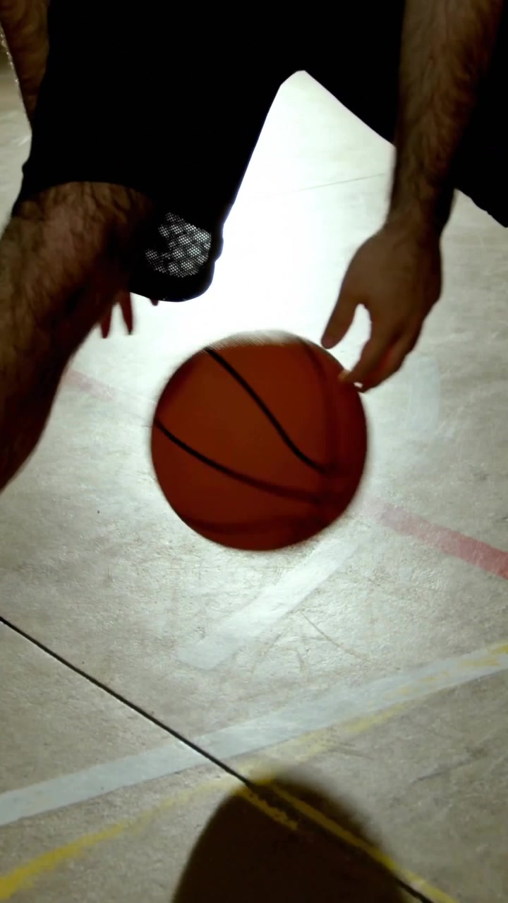Video vertical: Jugador de baloncesto botando el balón con la mano derecha, generando una superposición de 'me gusta'