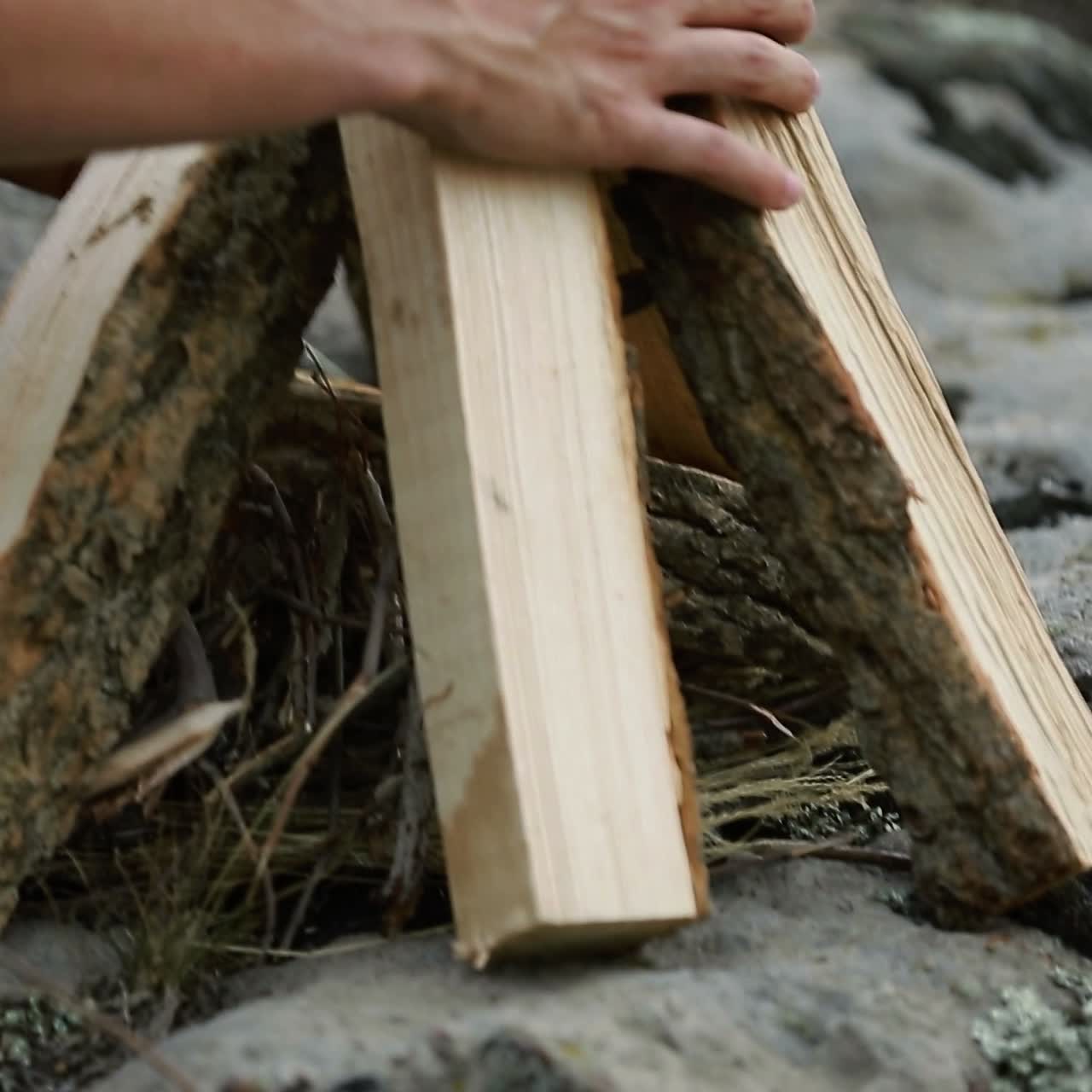 Making Fire In The Forest. Young man kindles a fire in summer wood