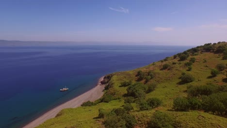 Aerial:-A-quiet-beach-with-a-fishing-boat-on-Lesbos,-near-Turkey