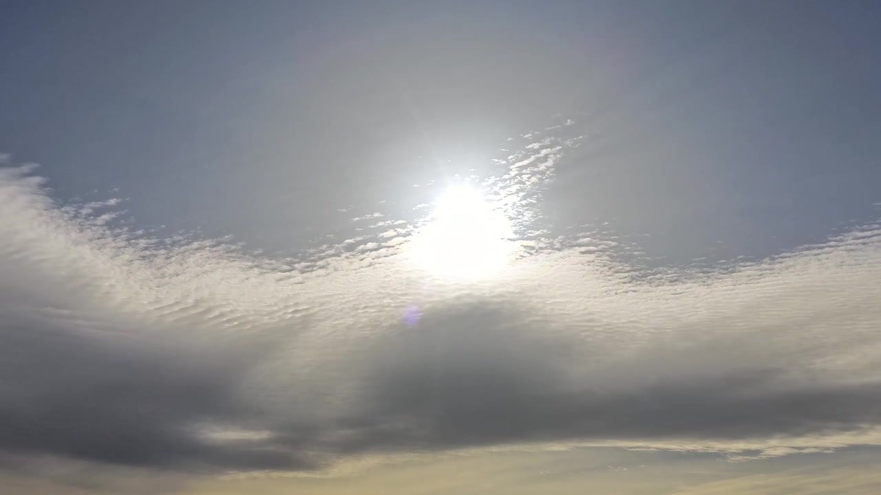 4K drone timelapse captures the sun rising from mesmerizing clouds with continuous light rays rippling through. Cinematic dawn skyscape features stunning sunbeams and shifting atmospheric light.