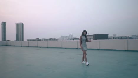 young woman in dress walks along roof in evening slow motion