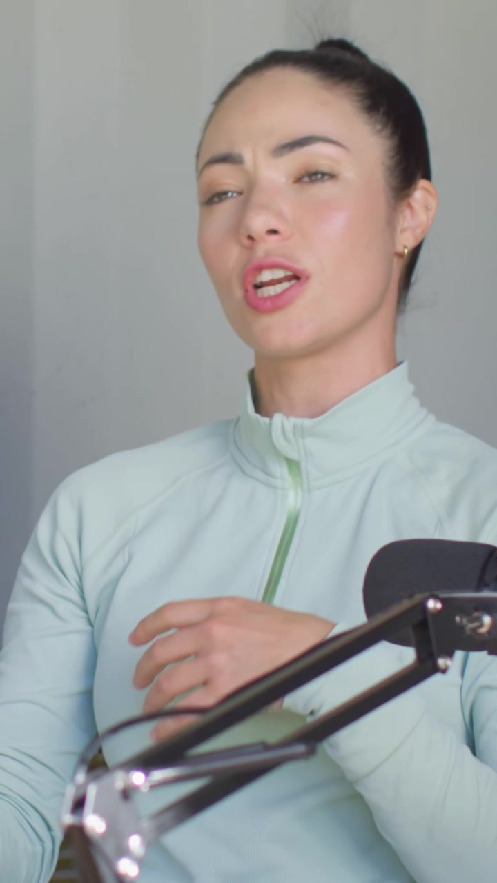 Video verticale: Donna con top color menta che si gira portando uno shaker, parlando in un microfono ad asta, in un angolo dello studio.