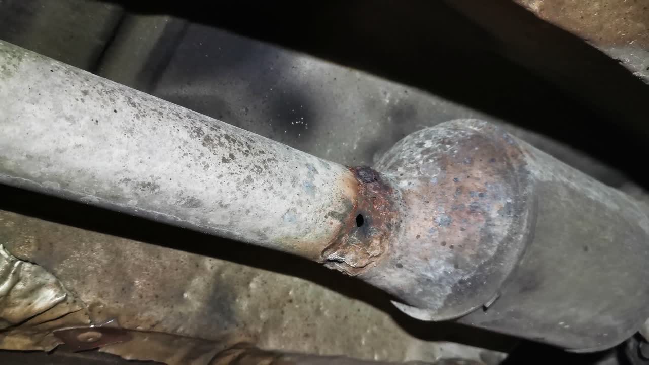 Foro nel tubo di scarico, vista da sotto l'auto in un centro assistenza