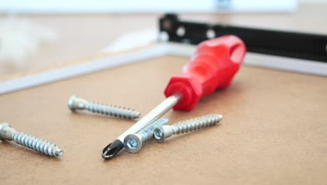 red screwdriver and screws on wood surface