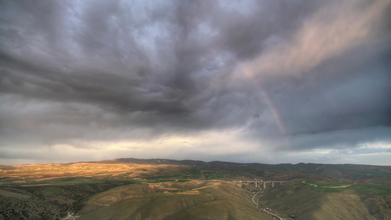 Vista Aérea de Arco-íris Sobre Colinas Onduladas e Vale ao Pôr do Sol