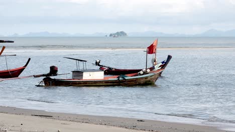 view of fishing boats moored along a windswept beach during the day in southern thailand