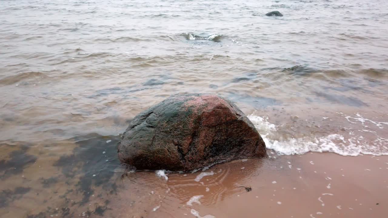 Estonia, Parco Nazionale di Lahemaa, onde sulla costa di Altja che colpiscono una pietra.