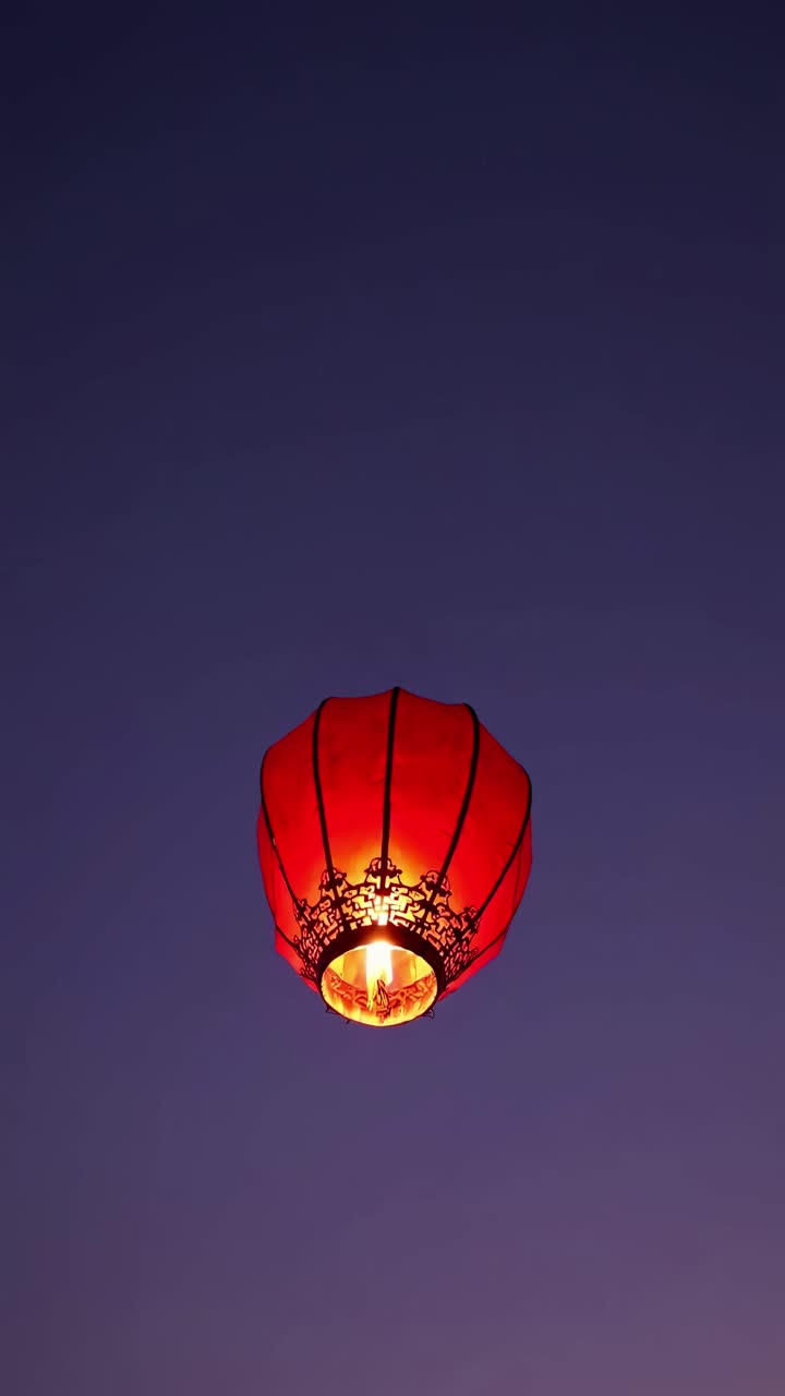 Aerial view of a glowing red lantern against a twilight sky, creating a serene and mystical