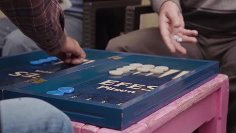 In-the-Cypriot-sidewalks,-two-elderly-guys-seated-and-engaged-in-a-game-of-tavla