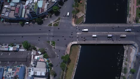 traffic bridge and overpass in ho chi minh city, vietnam, top down aerial tracking view on a sunny day featuring the canal, rooftops and road traffic