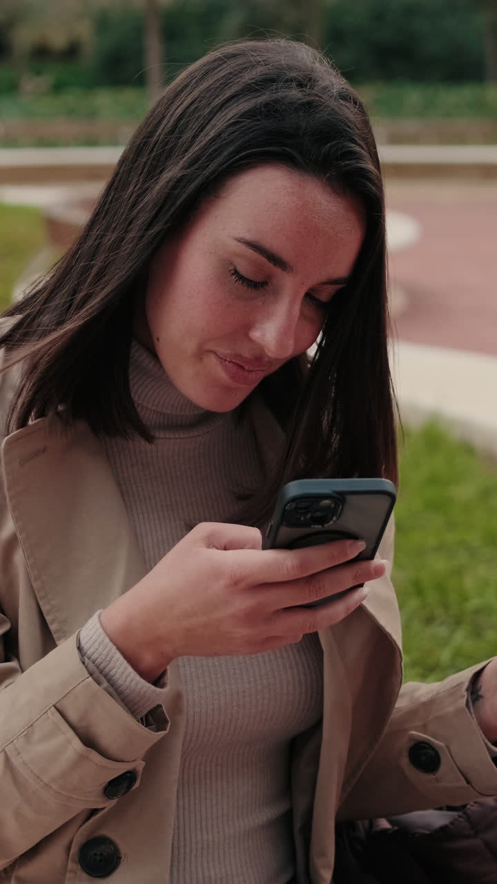 Giovane donna sorridente che usa lo smartphone e beve caffè all'aperto