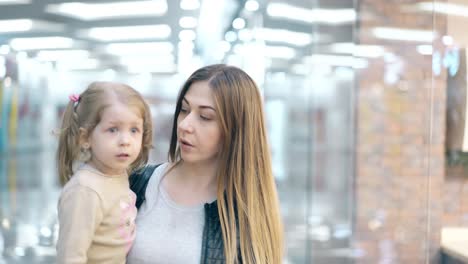 CU-4k-Young-mother-carries-little-daughter-in-her-arms-they-walk-along-the-business-center