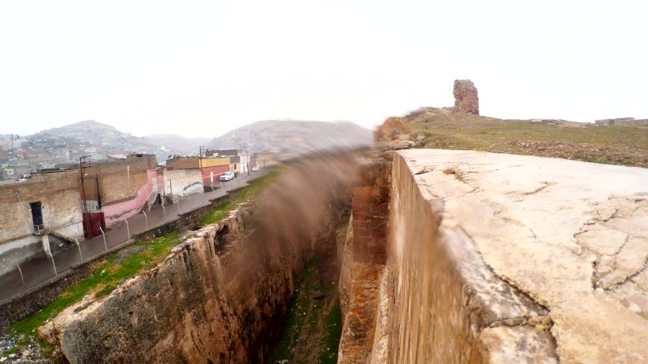 el foso hecho a mano del castillo de urfa divide las ruinas y el barrio pobre el pájaro vuela en el hoyo la nieve y la lluvia se ponen en la cámara