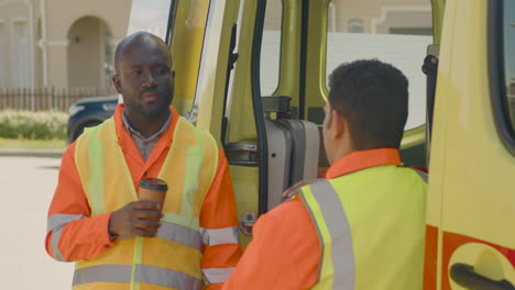 conductor de ambulancia bebiendo café y hablando con su colega latino