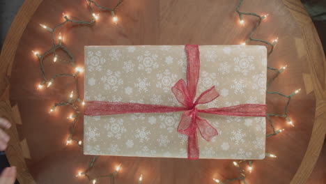 a christmas present is exchanged over a wood table