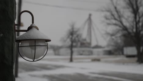 vintage looking light fixture and bulb hands on the side of old building in a small midwest, snow covered town on a cold winter day in december during christmas time