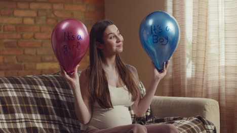 pregnant woman holding gender reveal balloons