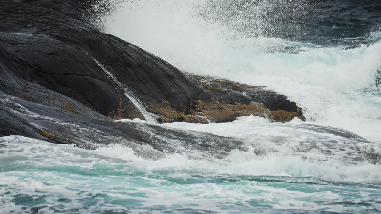 A dramatic close-up of a foamy turquoise wave, cresting near the rocky coast of Norway’s Atlantic Road.