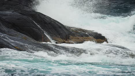 a dramatic close-up of a foamy turquoise wave, cresting near the rocky coast of norway’s atlantic road.