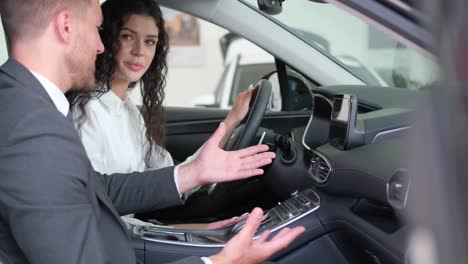a man and a woman are conversing in a vehicle sitting in the front seats a man and a woman are conversing inside a luxurious personal car seated in the front near the steering wheel and automotive mirror