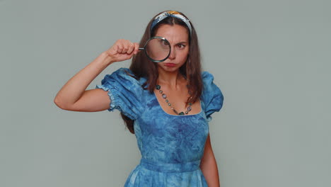 Researcher-scientist-woman-holding-magnifying-glass-near-face,-looking-to-camera-with-big-zoomed-eye