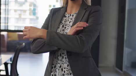 Portrait-of-caucasian-businesswoman-wearing-face-mask-with-arms-crossed