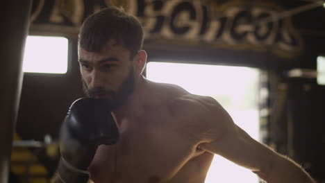 muscular boxer training with punching bag. boxing man training in slow motion