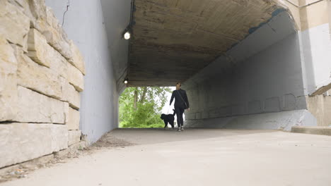 Low, wide angle shot of a young woman walking her dog through an urban environment