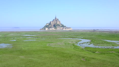 Aufschlussreiche-Aufnahme-Des-Mont-Saint-Michel,-Verstecken-Der-Kamera-Hinter-Einem-Alten-Schuppen-Und-Dann-Erhöhen-Der-Höhe-Der-Drohne