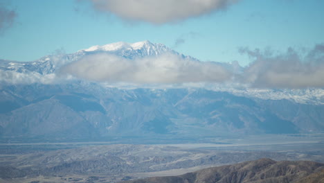 Una-Vista-Fascinante-De-Los-Picos-De-Las-Montañas-Cubiertas-De-Nieve-Con-Nubes-Que-Se-Mueven-Lentamente,-Creando-Un-Espectáculo-Natural-Impresionante