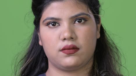 young overweight beautiful indian businesswoman against green background