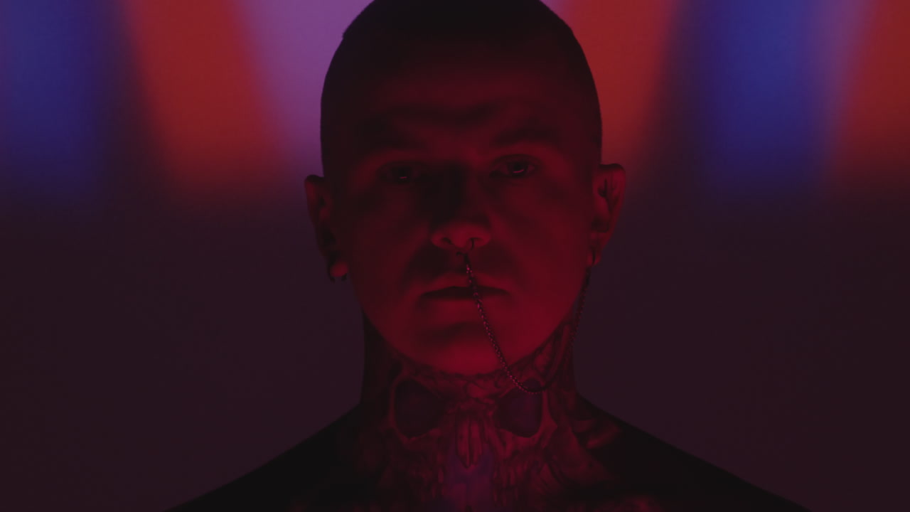 Tattooed Man with Nose Chain in Dark Studio