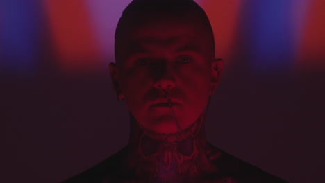 tattooed man with nose chain in dark studio