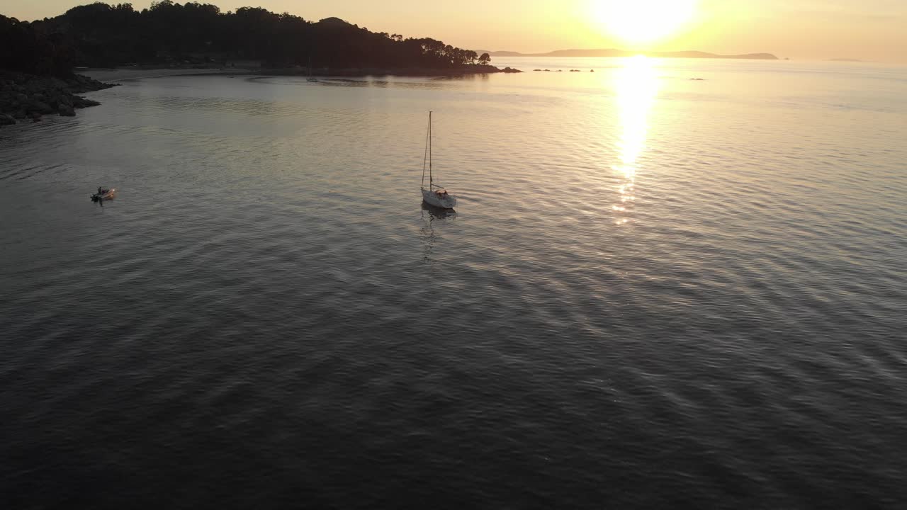 Magnifica ripresa aerea che mostra la costa baciata dal sole della spiaggia di Bueu, Galizia, Spagna, lento movimento della telecamera verso l'alto in uno splendido tramonto arancione che mette in mostra lo stile di vita dello yachting europeo