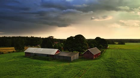 rural landscape with farm field and farm houses on a cloudy day near hjo, sweden - aerial shot