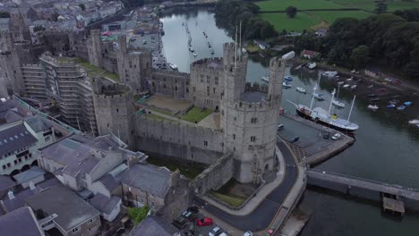 ancient caernarfon castle welsh harbour town aerial view medieval waterfront landmark high up left dolly