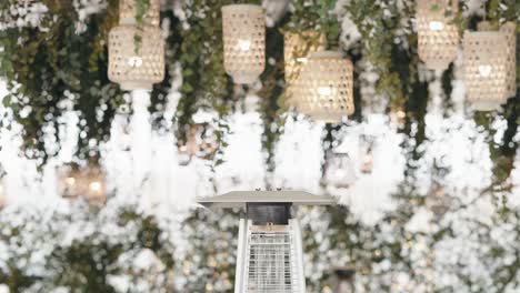 close up of outdoor heater under floral ceiling with hanging lanterns and soft lights