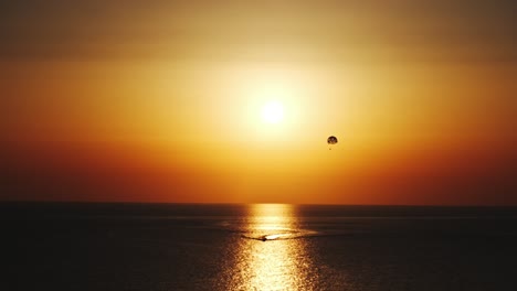 parasailing parascending parakiting,paragliding at cinematic sunset by boat in ten bit four k sixty fps in distance