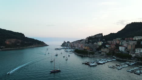 Vista-Aérea-De-Yates-Navegando-Y-Estacionados-En-El-Puerto-Del-Pueblo-De-Portovenere-En-Italia-Rodeado-De-Acantilados-Y-Pequeños-Edificios-Multicolores-En-La-Costa