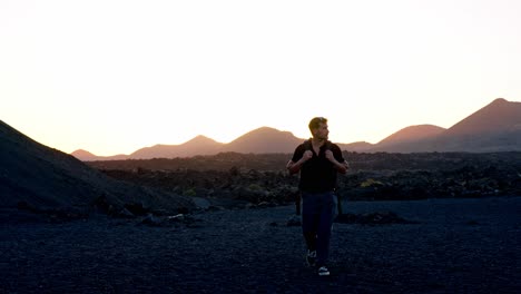 a lone man walks through the stark, volcanic landscape of the volcán del cuervo trail in lanzarote, canary islands, spain.