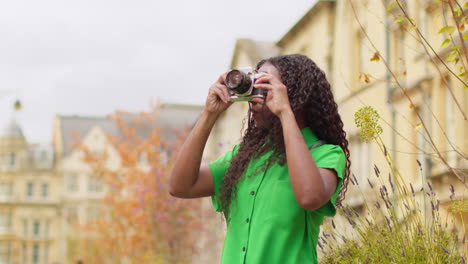 Female-Tourist-With-Camera-On-Vacation-In-Oxford-UK-Exploring-City-Walking-Along-Broad-Street-Taking-Photos-1