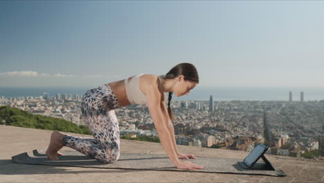 Eine-Sportliche-Frau-Schaut-Sich-Während-Des-Yoga-Trainings-Im-Freien-Ein-Video-Auf-Einem-Tablet-An