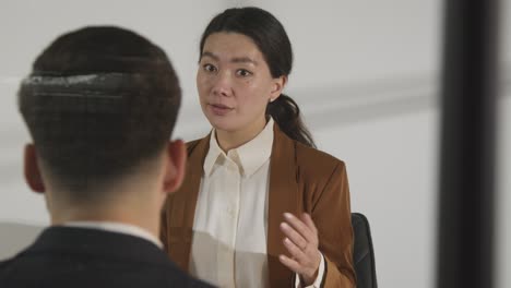 male candidate being interviewed in office for job by female interviewer viewed through window 3