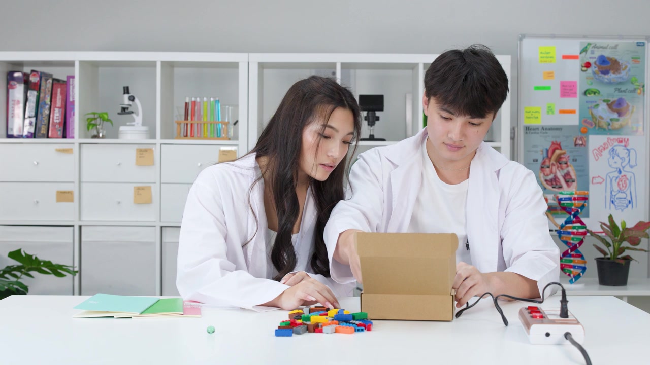 Hai sinh viên mặc áo blouse hợp tác thực hiện dự án STEM sử dụng gạch nhựa và hộp