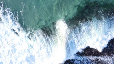 Olas-Con-Flecos-Blancos-Rodando-Desde-La-Parte-Superior-De-La-Pantalla-Hacia-Las-Rocas-Del-Océano-Playa-Tamarama-Sydney-Australia-Pov-Seguimiento-De-Drones-A-La-Izquierda