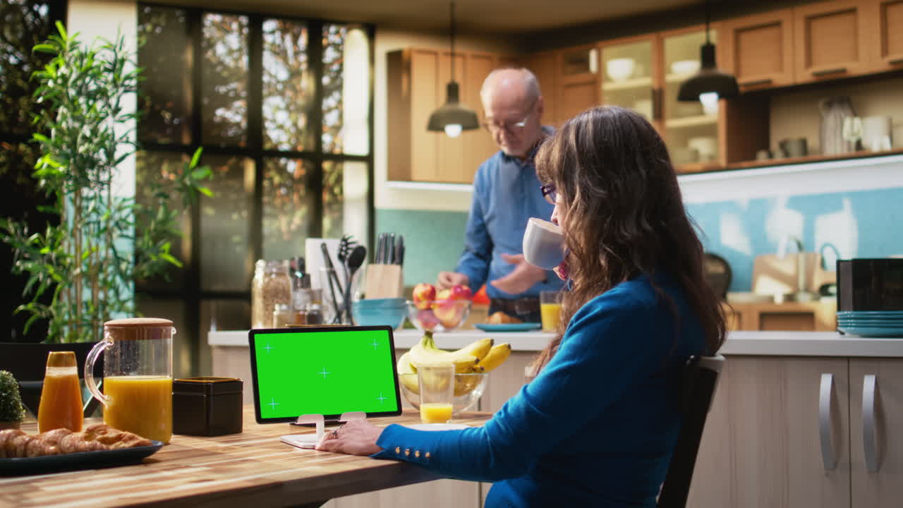 Isolated mockup tablet with old woman enjoying breakfast at kitchen table