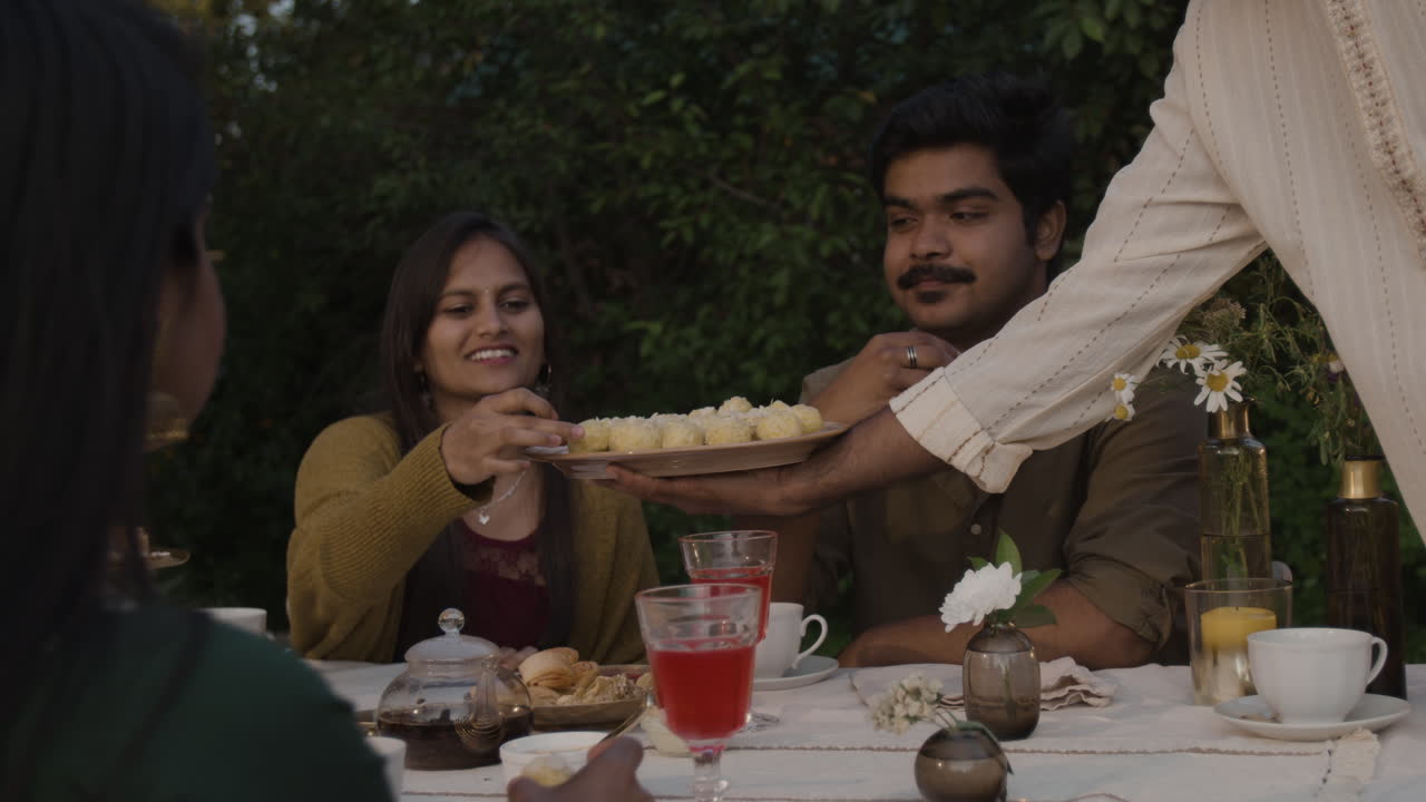 People enjoying an outdoor meal, sharing food and drinks at a social gathering